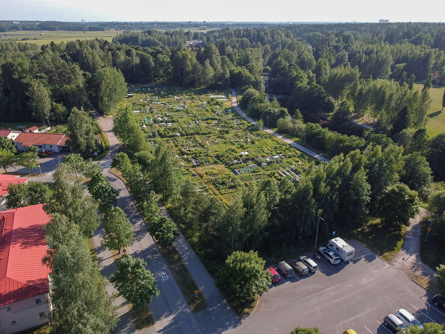 Aerial view of allotment gardens surrounded by forest on the edge of a Finnish town.