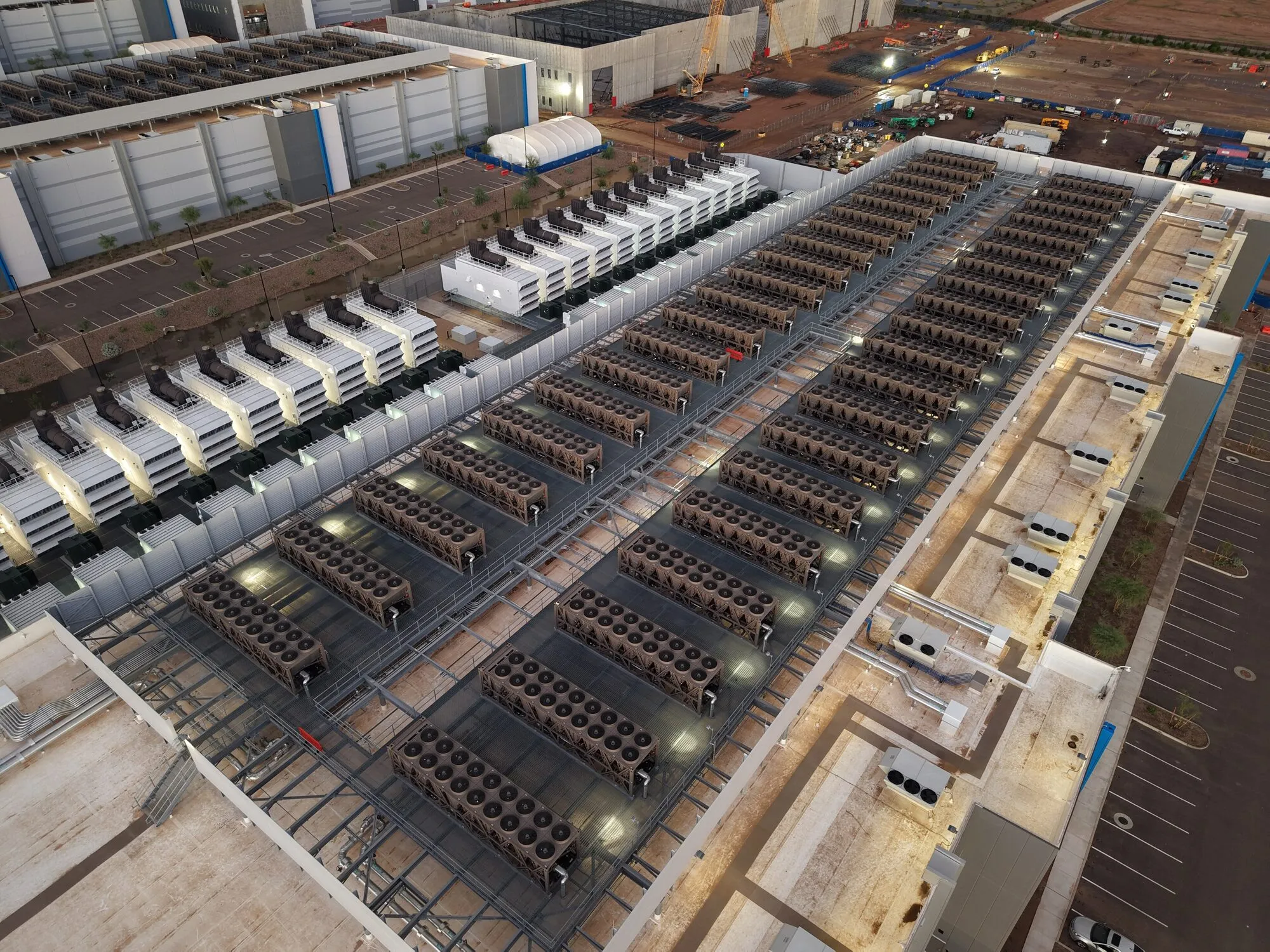 An aerial view of a large data centre roof covered in rows of cooling units and generators.