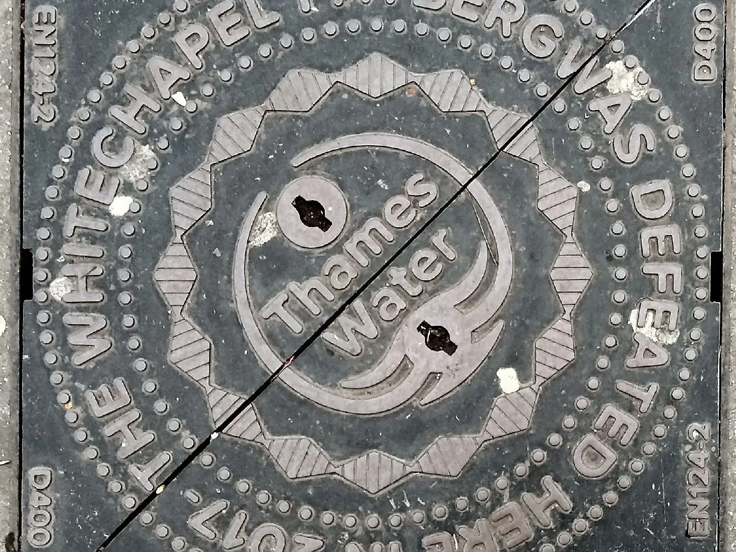 Una tapa de boca de ferro colat rodona en un paviment de Londres amb el logotip de Thames Water i les paraules "The Whitechapel fatberg was defeated here in 2017".