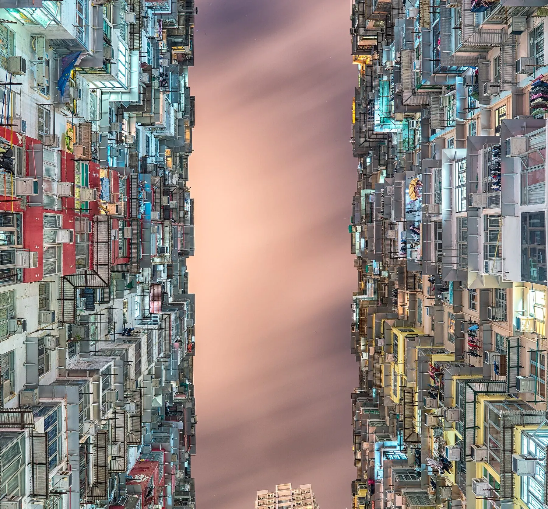 Kis lakótornyok zsúfolódnak egy keskeny udvar körül Hongkongban.