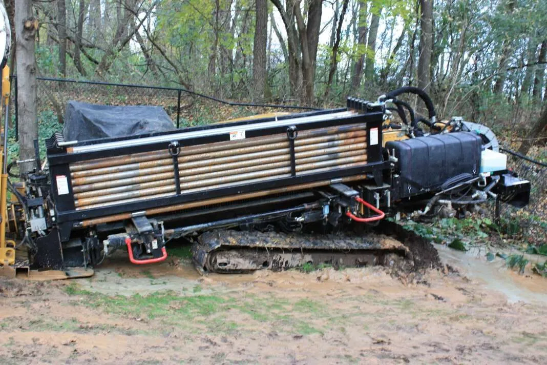 A tracked horizontal directional drilling machine on a muddy site in woodland.