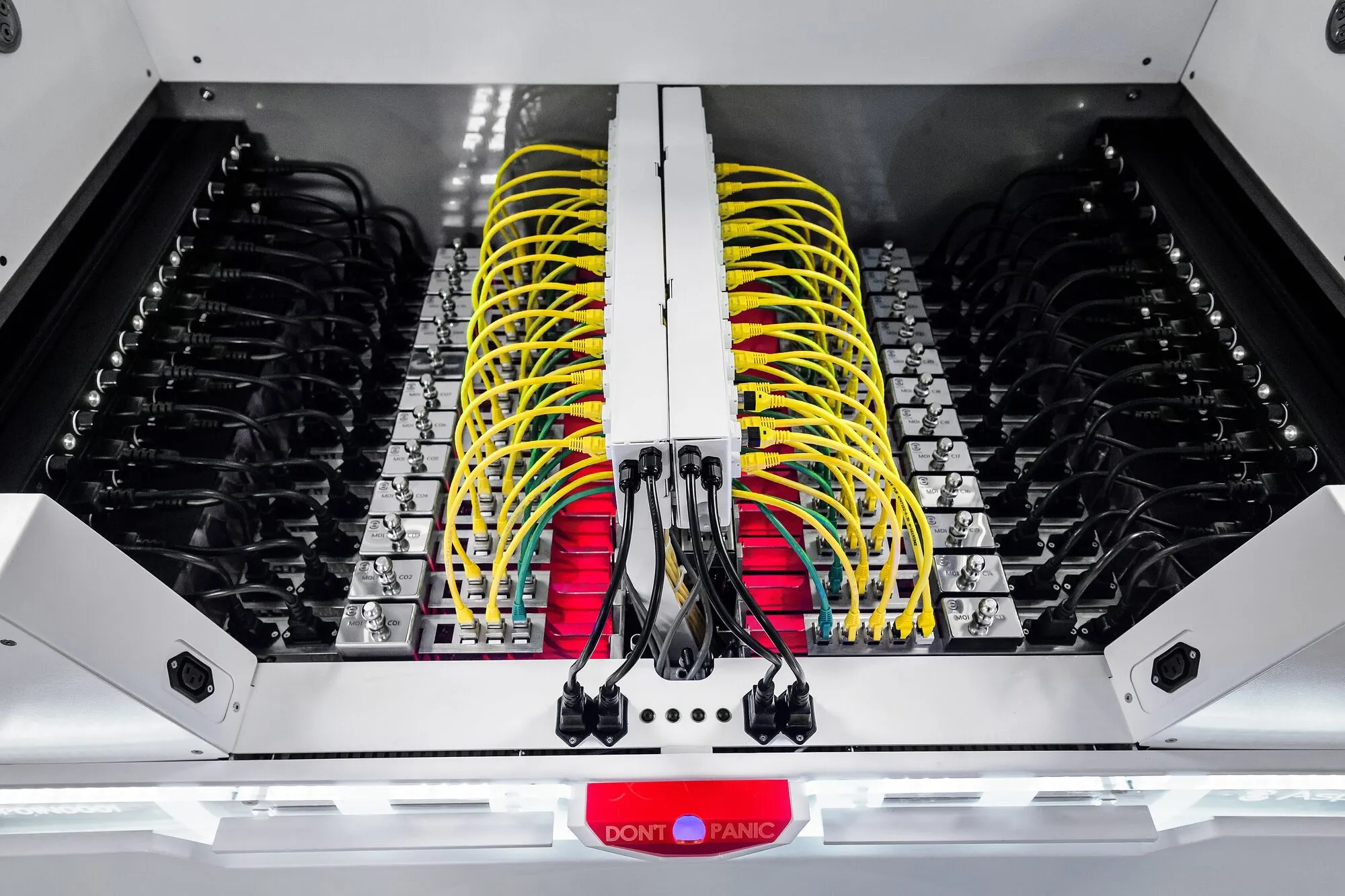 Rows of computer servers standing in liquid inside an open immersion cooling tank, with yellow cables.