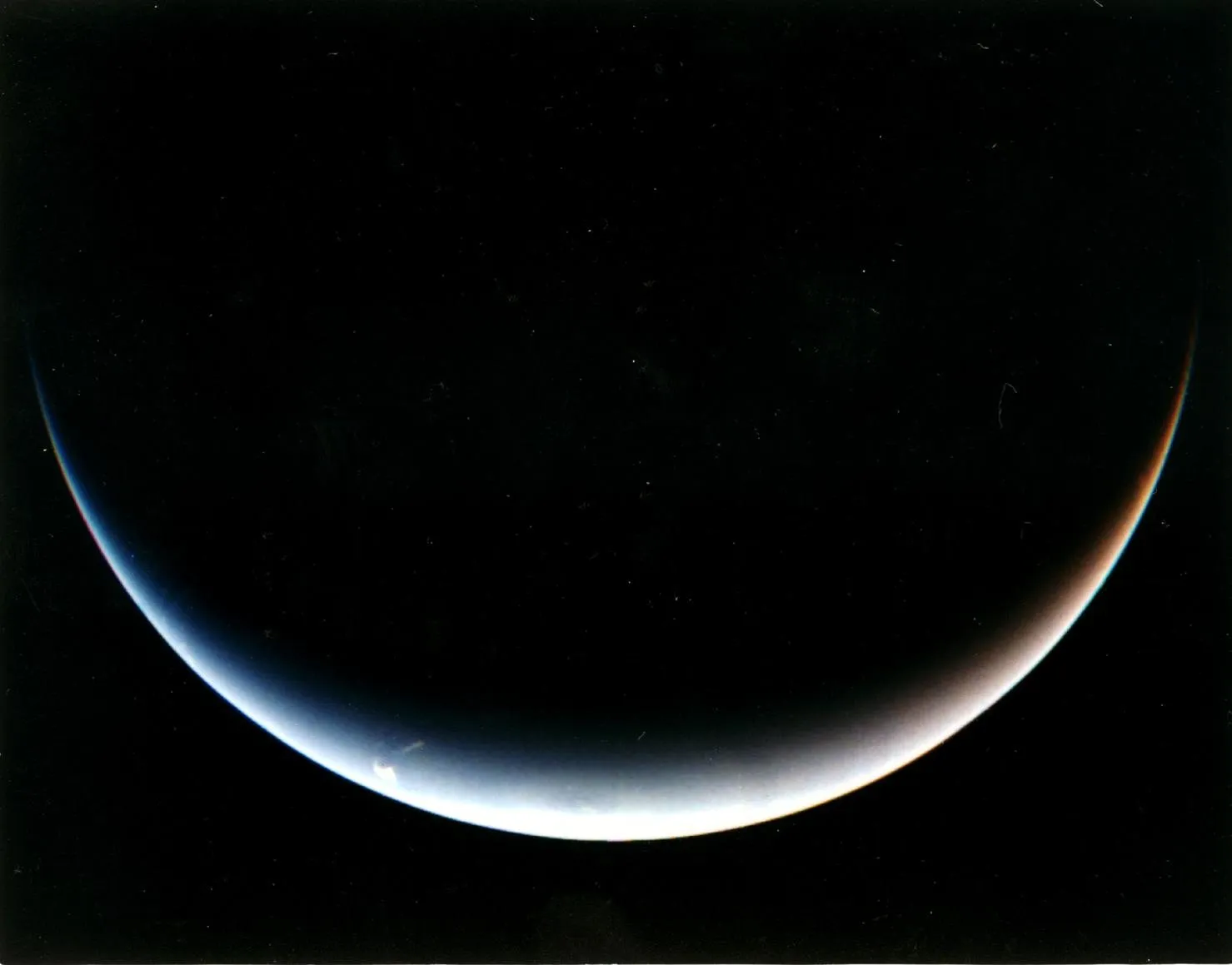A thin crescent of Neptune against black space.