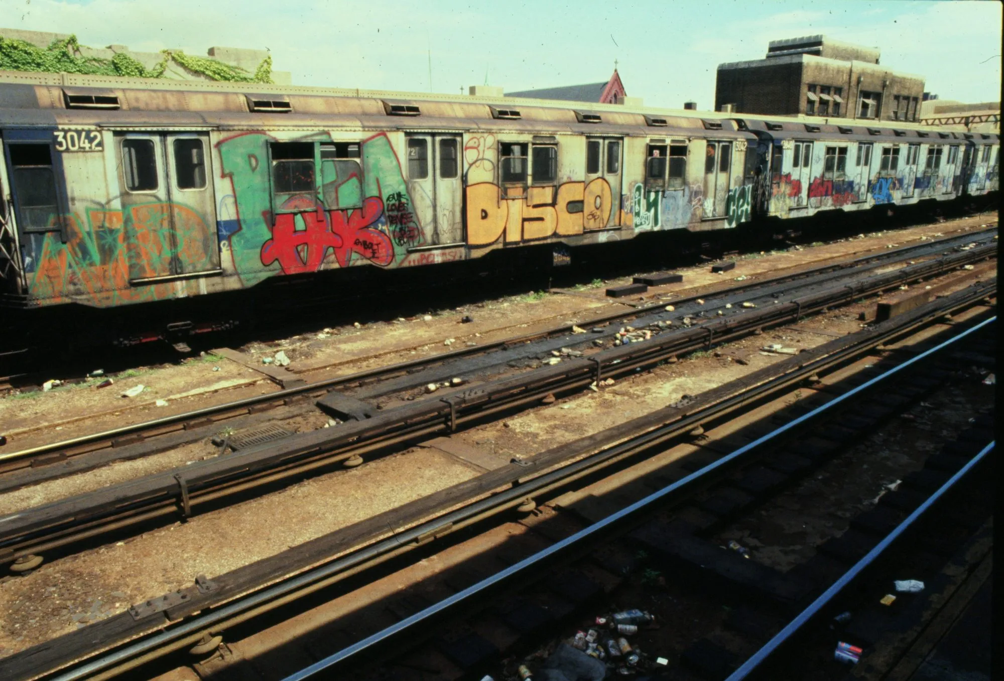 Oude New York metrokarretjies bedek met geverfde graffiti, staan in 'n ooplug-spoorwegwerf.