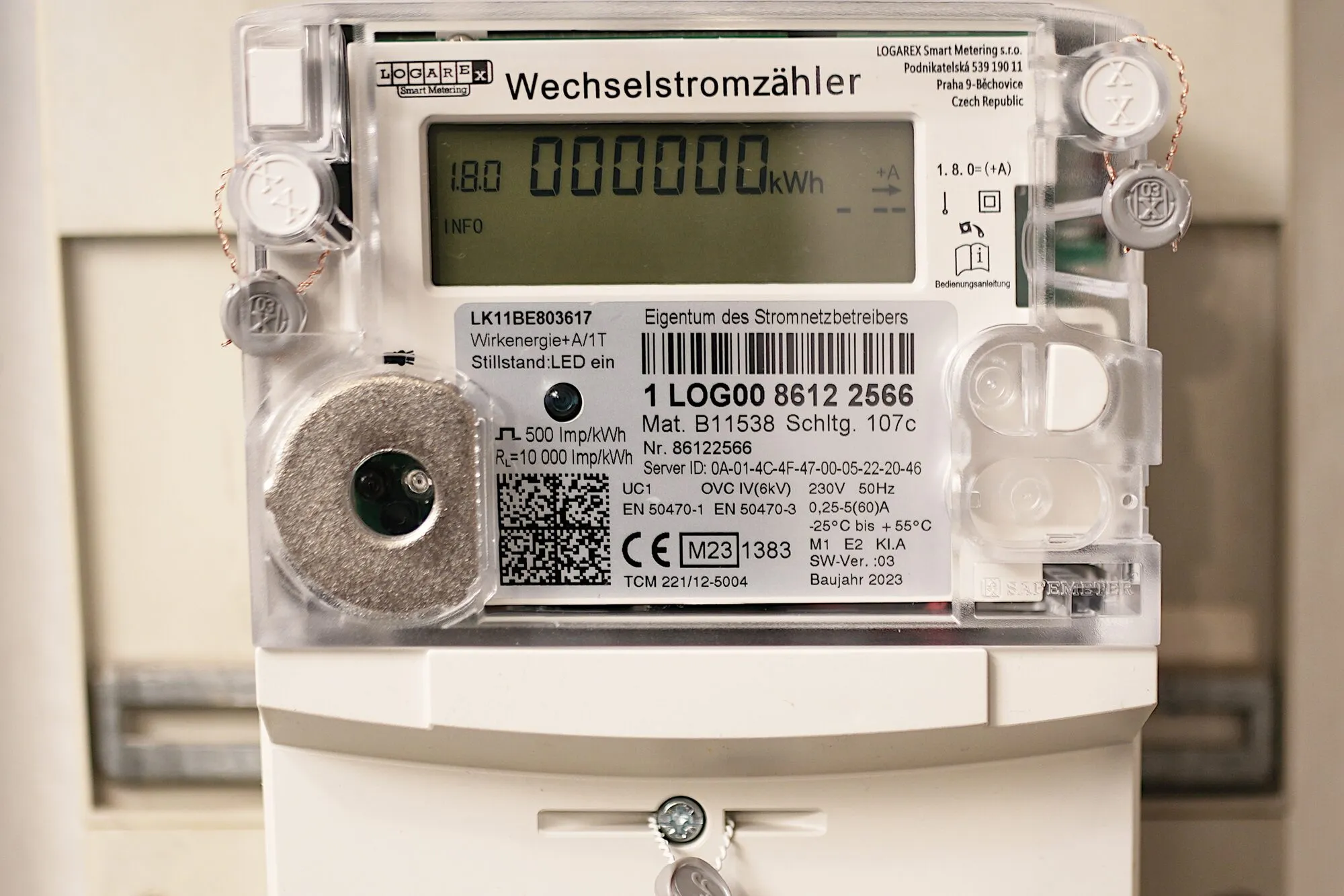 A digital household electricity meter with a small display, mounted on a meter board.