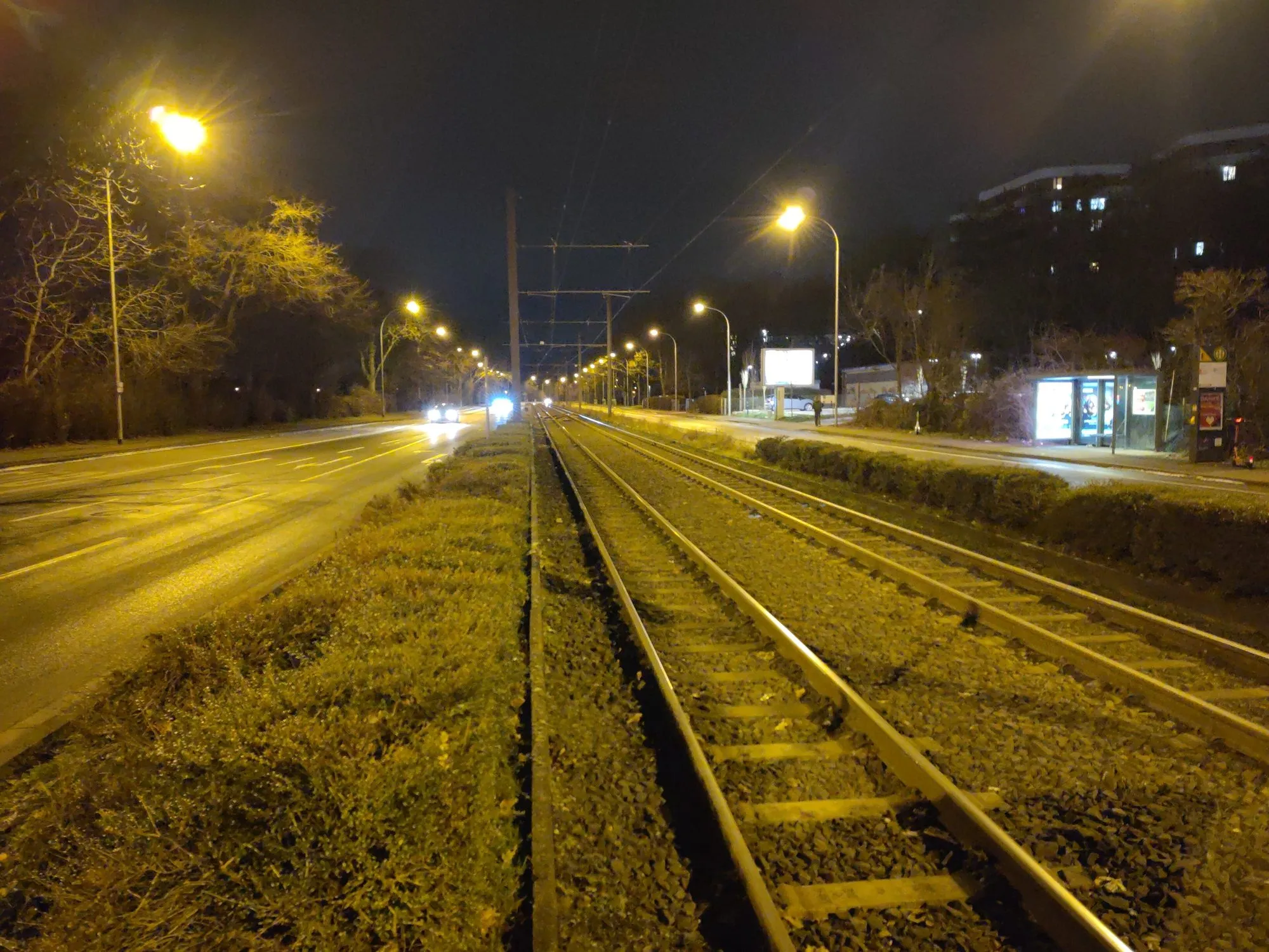 'n Tramlyn en pad by nagverligting deur 'n ry oranje natriumstraatliggies in Mainz, Duitsland.