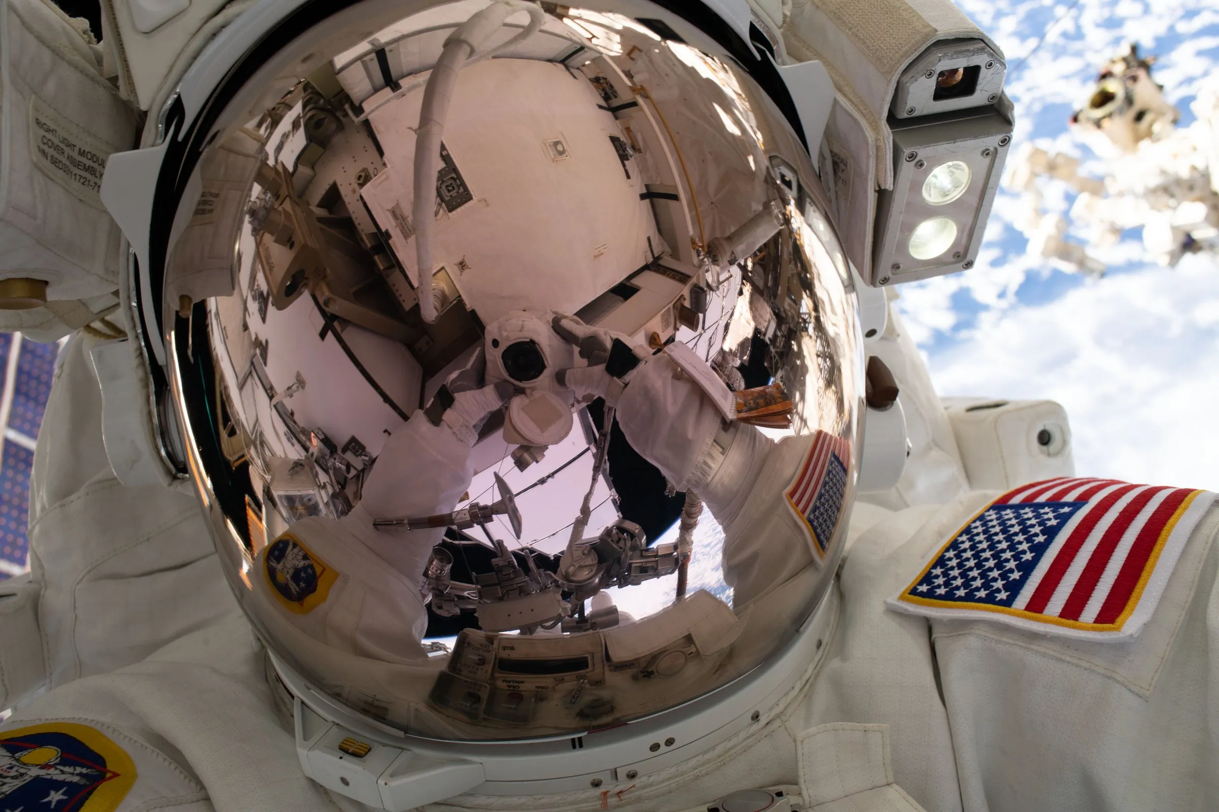 An astronaut's reflective visor during a spacewalk, with Earth reflected in it.