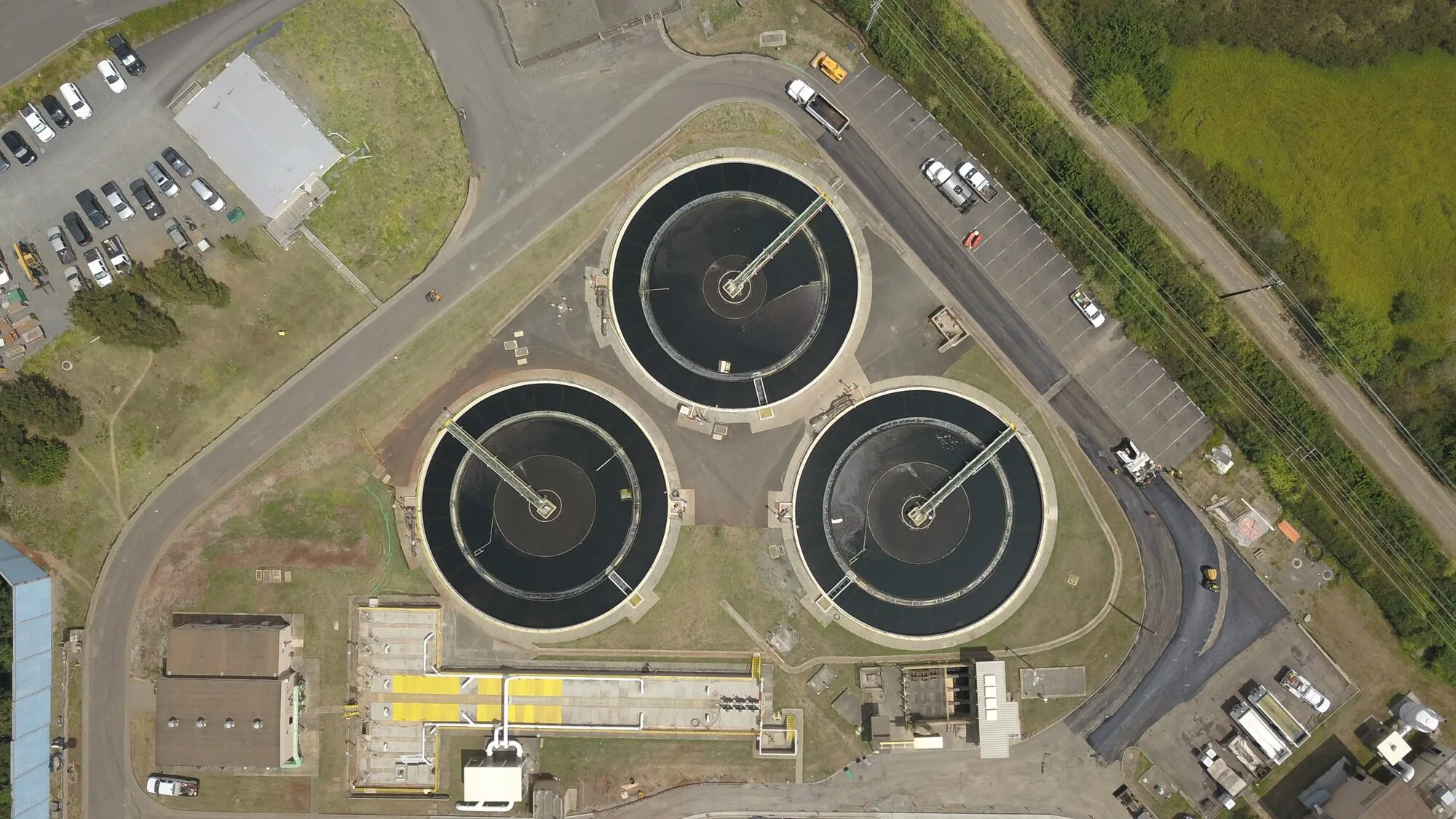 Aerial view of three round settling tanks at a wastewater treatment plant.